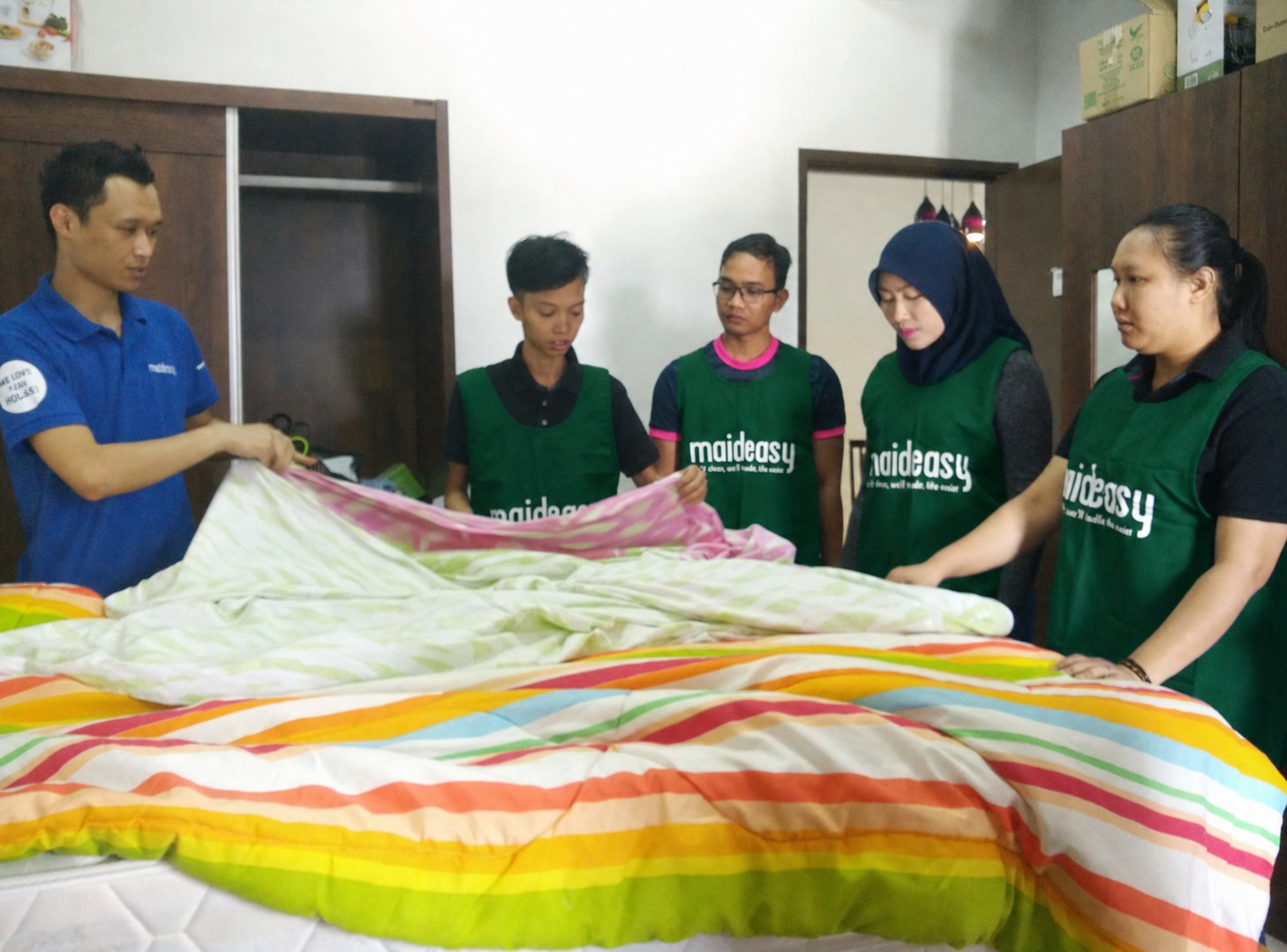 Maideasy team learning proper bed-making and linen folding during training